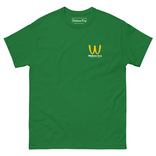 A green short-sleeve crewneck t-shirt with a small yellow and white 'Wolves Cry' logo printed on the left chest, displayed on a clean white background. McDowells restaurant tee shirt, coming to America.