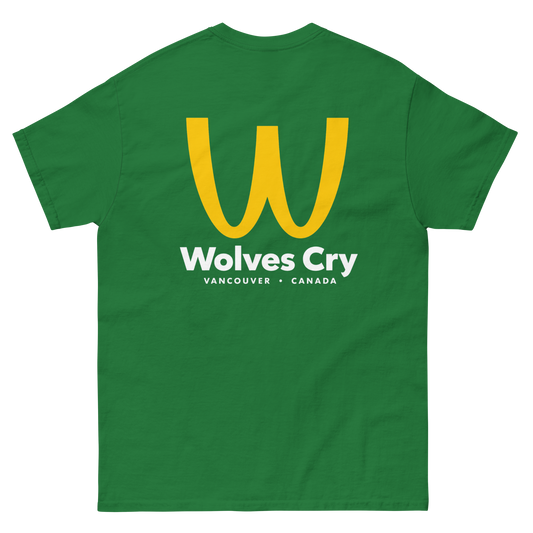 A green short-sleeve t-shirt with a large yellow 'W' logo and white text reading 'Wolves Cry' and 'VANCOUVER • CANADA' on the front, shown against a plain white background. McDowells restaurant tee shirt, coming to America parody bootleg 