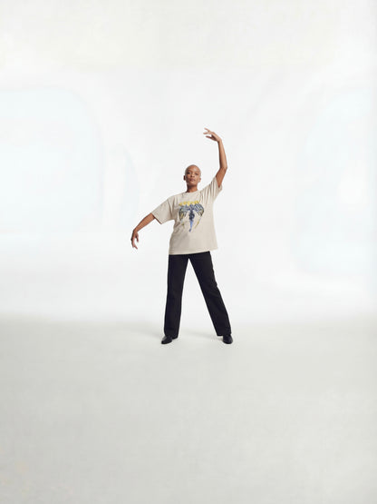 Model in motion wearing Wolves Cry Originals Angels oversized tee in bone demonstrating movement, oversized fit, and heavyweight streetwear construction.