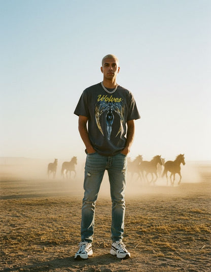 Model wearing the Wolves Cry Originals Angels tee in vintage black in a desert scene with running horses, inspired by vintage band tee aesthetics.
