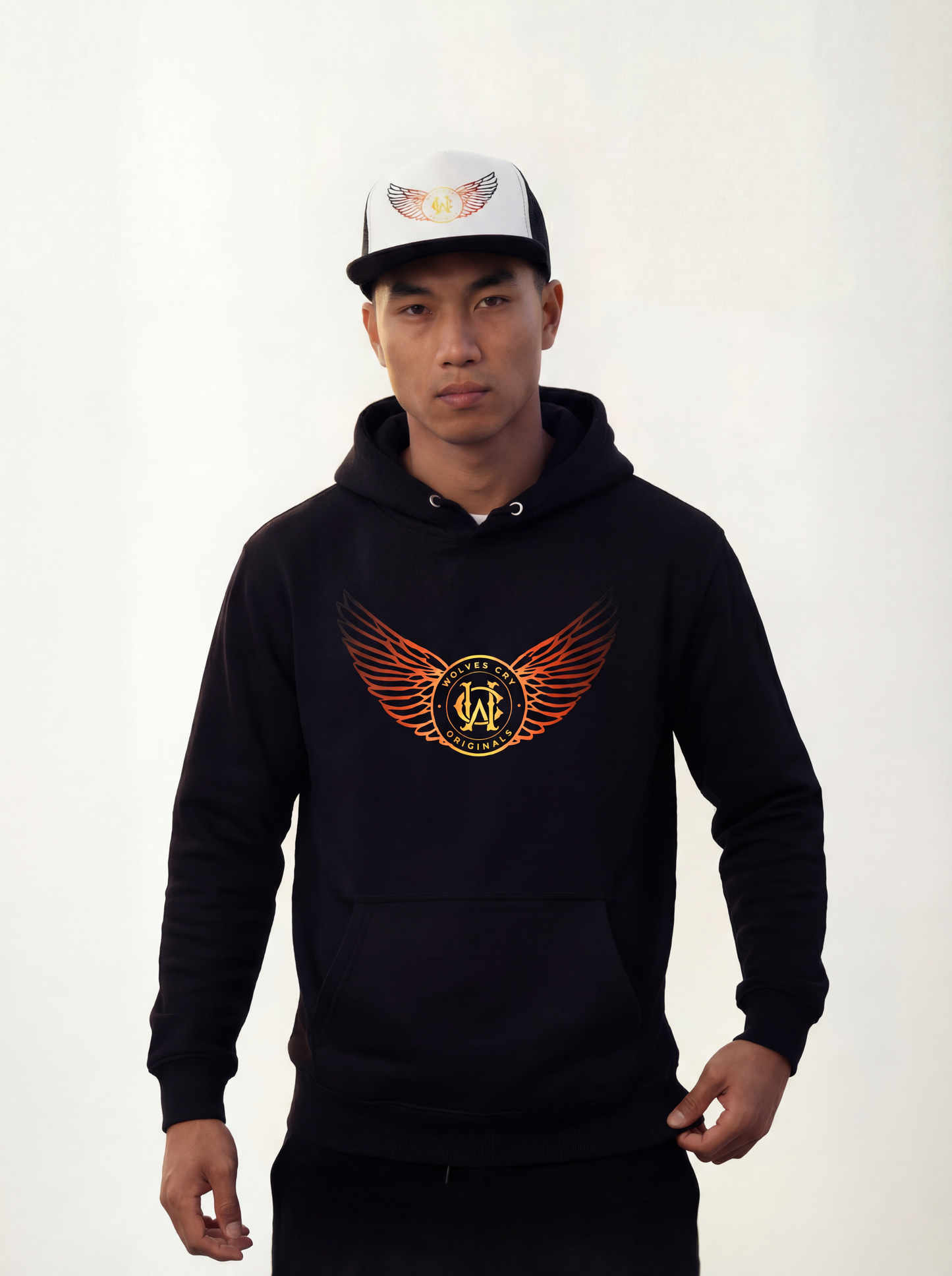 Person wearing a wolves cry originals black hoodie with a logo and a white cap with a design on a plain background