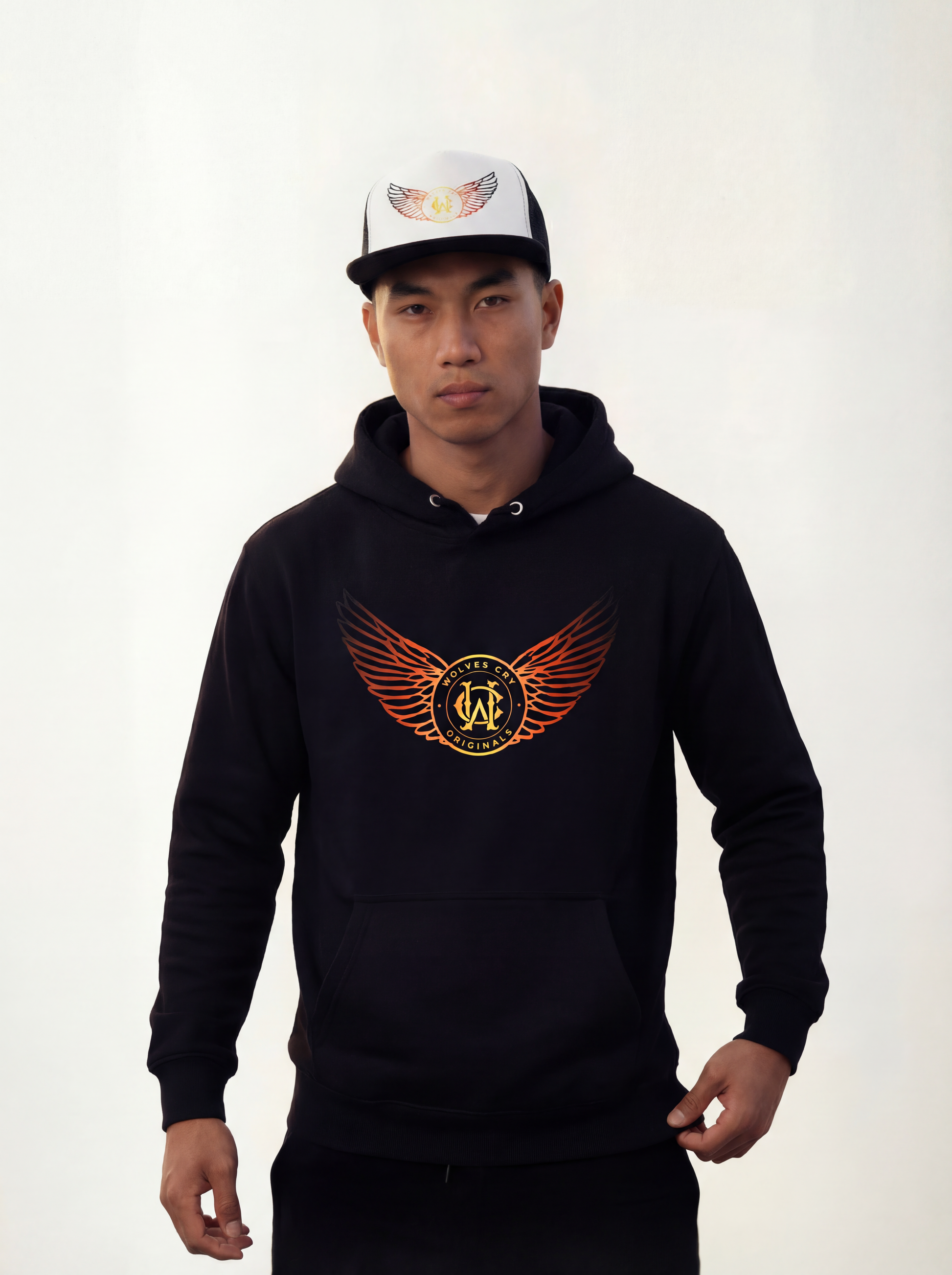 Person wearing a wolves cry originals black hoodie with a logo and a white cap with a design on a plain background