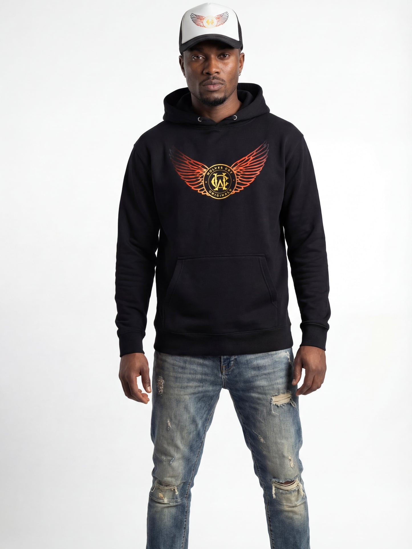 Man wearing a black hoodie with a logo and distressed jeans on a white background