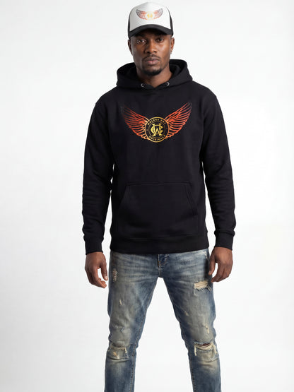 Man wearing a black hoodie with a logo and distressed jeans on a white background