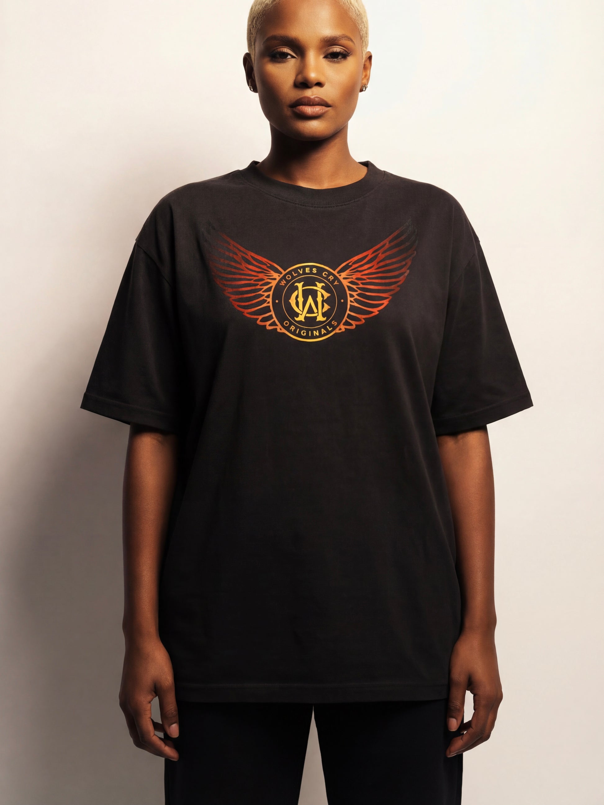 Person wearing a black t-shirt with a logo on a plain background
