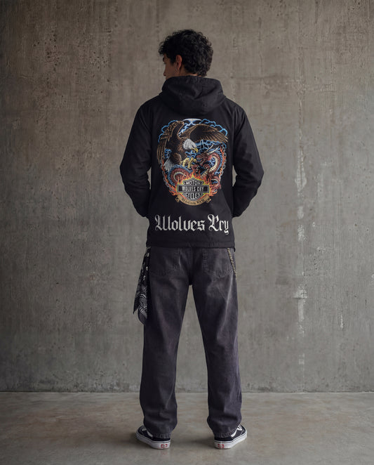 Person wearing a black windbreaker hoody with a colorful design on the back against a gray concrete wall. Wolves cry jacket 