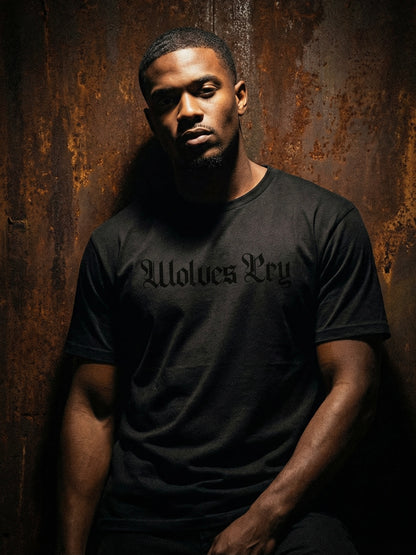 Man wearing a black t-shirt with 'Wolves Cry' text against a rusty metal background
