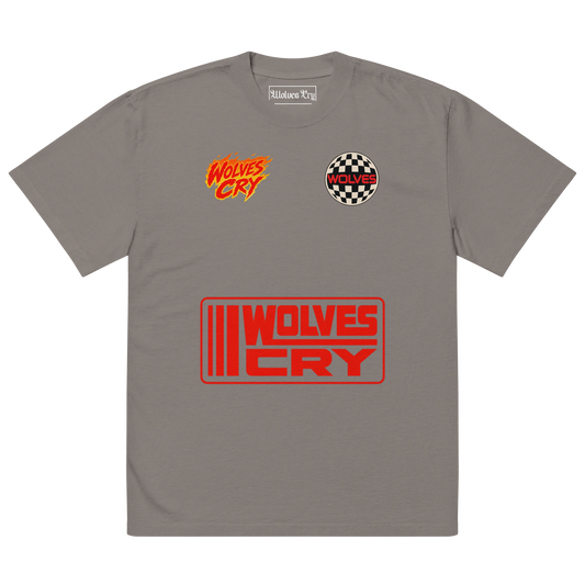 A gray short-sleeve t-shirt with 'Wolves Cry' branding, featuring a red and orange logo on the left chest, a circular checkered logo on the right chest, and a large red and orange rectangular logo on the front.